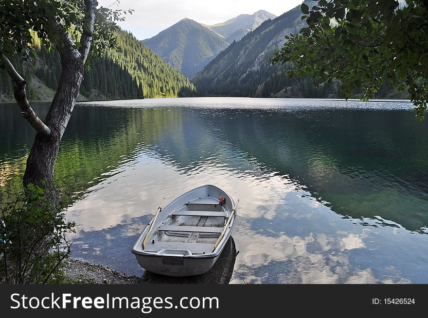 White rowing boat towed on Kolsai lake in tien shan mountains kazakhstan. White rowing boat towed on Kolsai lake in tien shan mountains kazakhstan