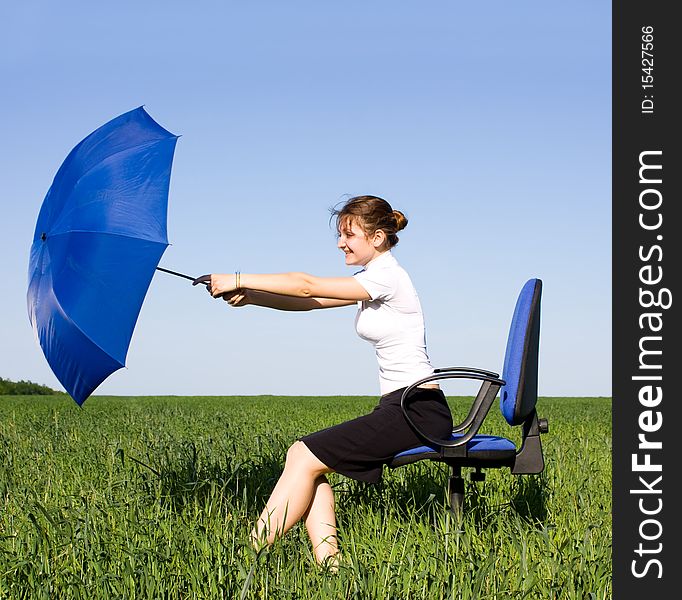 Businesswoman sitting on a field in a chair with umbrella. Businesswoman sitting on a field in a chair with umbrella