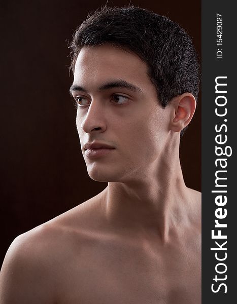 A fairly close up portrait of a young man against a dark background looking off to the side intensely. A fairly close up portrait of a young man against a dark background looking off to the side intensely