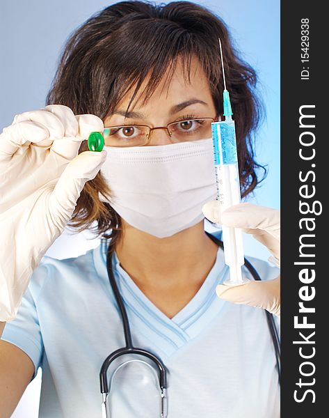 Confident female doctor holding a green pill and a syringe