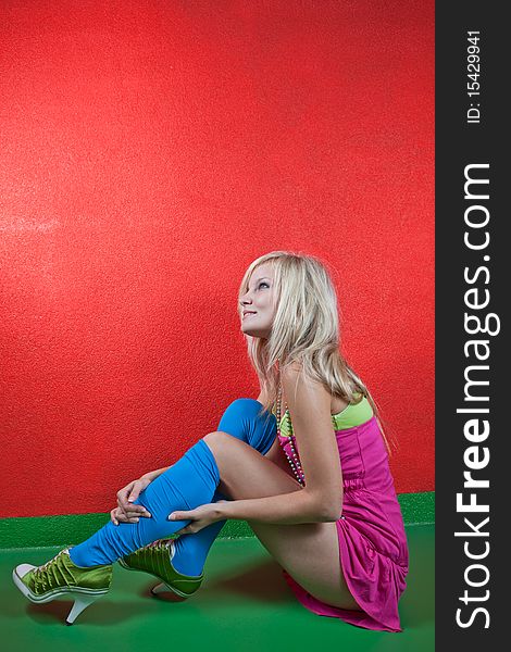 Beautiful young female photo model wearing high red boots posing in front of a red wall. Beautiful young female photo model wearing high red boots posing in front of a red wall