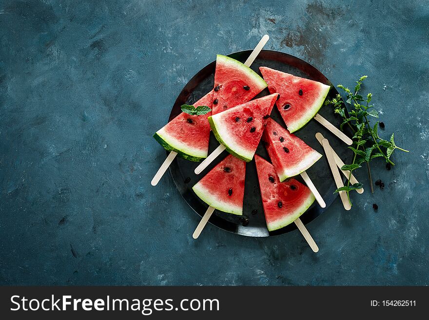 Watermelon slice popsicles on a blue background, top view