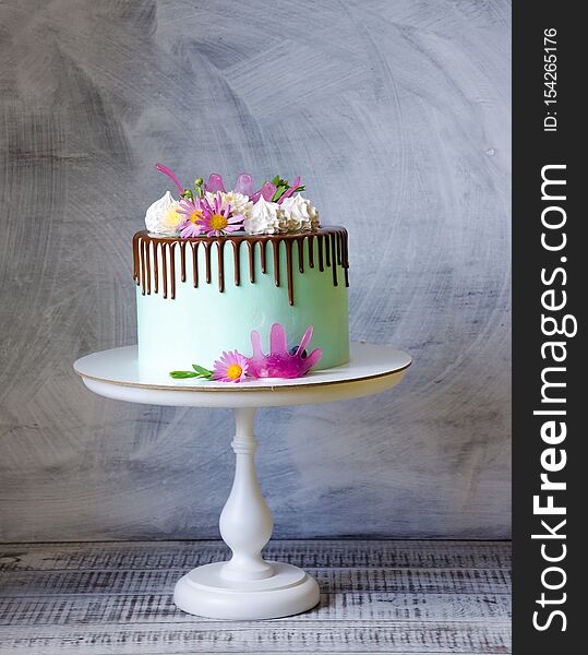 Tasty chocolate drip cake decorated with zephyr and flowers