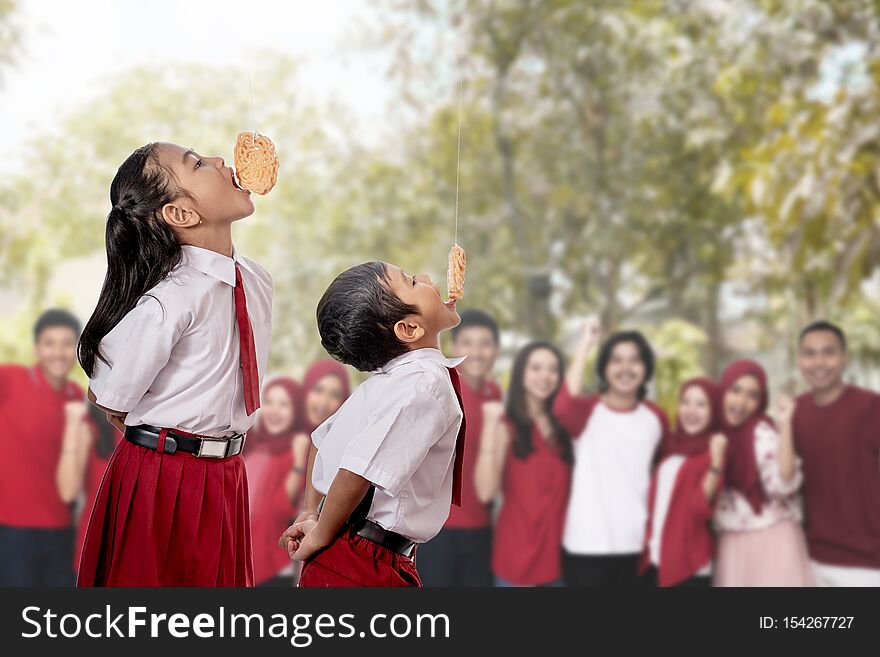 Kids against each other eating indonesian cracker on independence day