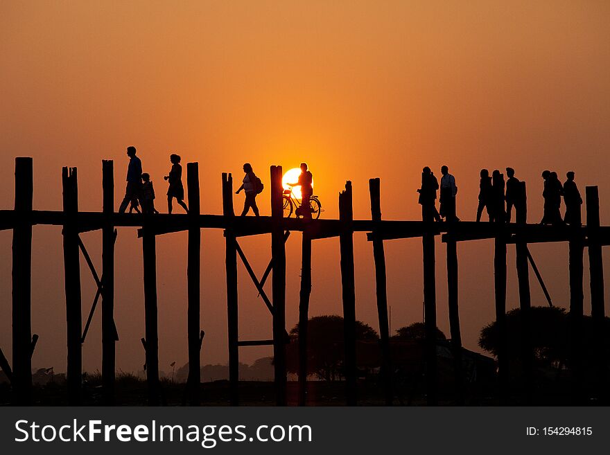 Silhouetted people on U Bein Bridge at sunset, Amarapura, Mandalay region, Myanmar. Burma. The longest and oldest teak