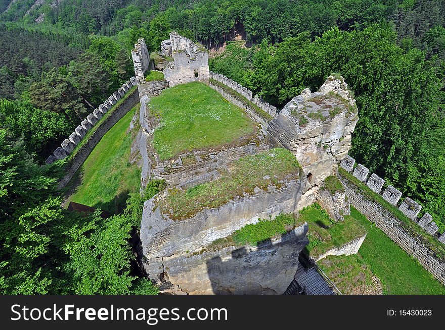 Medieval castle ruins in green forest, aerial view.