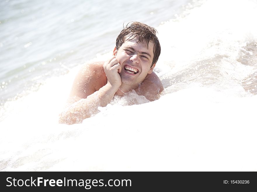 Young smiling men on waves at beach. Outdoor photo.