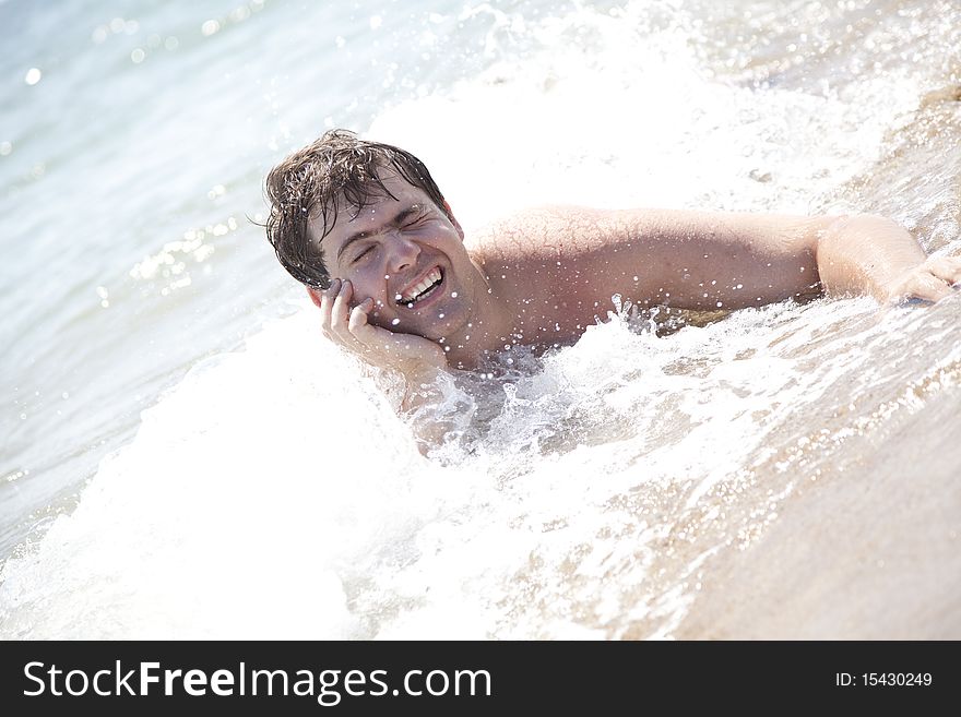 Young smiling men on waves at beach. Outdoor photo.