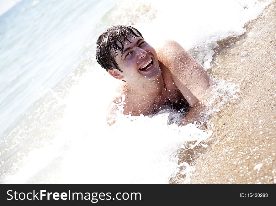 Young smiling men on waves at beach.