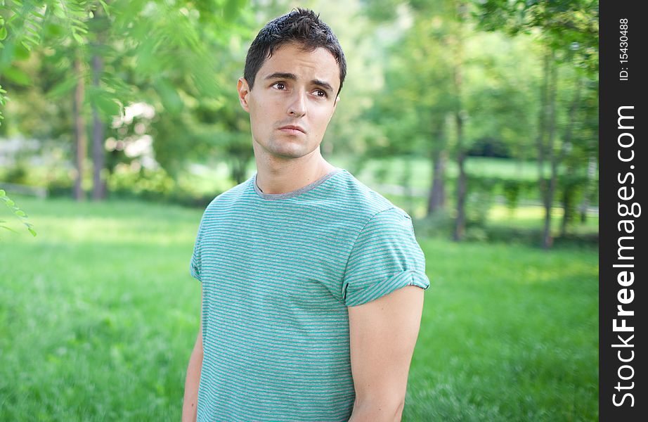 Portrait of a handsome young man while outdoors in a park on a lovely summer day