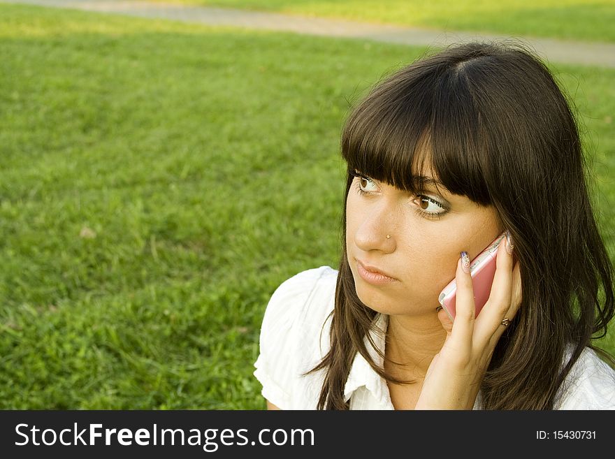 Young beautiful woman on the phone in the park. Young beautiful woman on the phone in the park