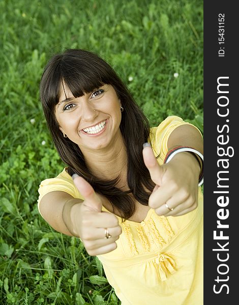 Young beautiful woman is smiling in a park and shows the Thumb Up. Young beautiful woman is smiling in a park and shows the Thumb Up