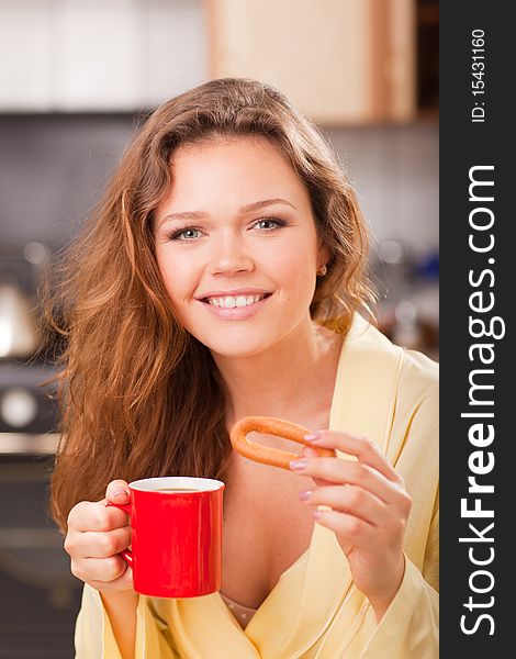 Attractive young adult with red cup of tea in the kitchen