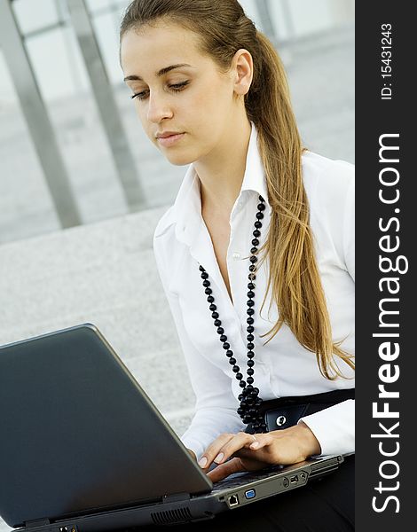 Business woman running on a laptop. He sits on the stairs office building. Business woman running on a laptop. He sits on the stairs office building