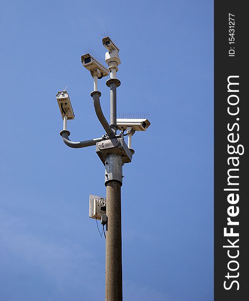 Cluster of security cameras against a blue sky. Cluster of security cameras against a blue sky