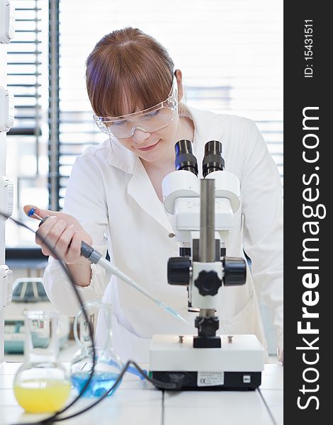 Pretty female researcher using a microscope in a lab