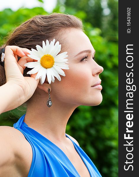 Profile of pretty caucasian young adult with camomile in garden. Profile of pretty caucasian young adult with camomile in garden