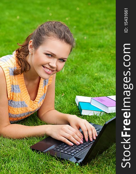Attractive caucasian girl lying on grass with laptop and smile to the camera. Attractive caucasian girl lying on grass with laptop and smile to the camera