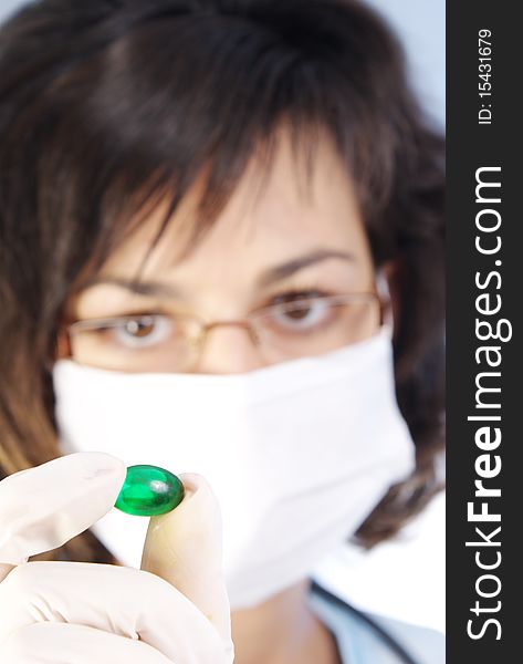 Confident female doctor holding a green pill