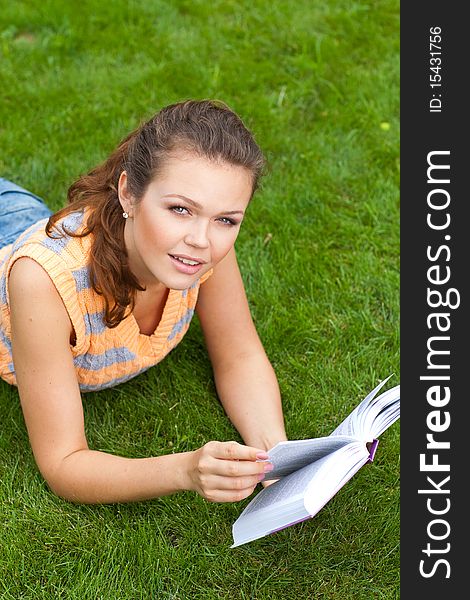 Attractive young adult reading a book on grass. Attractive young adult reading a book on grass