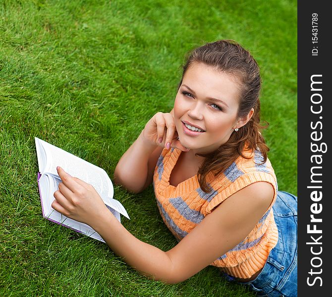 Attractive caucasian girl lying on grass with book. Attractive caucasian girl lying on grass with book