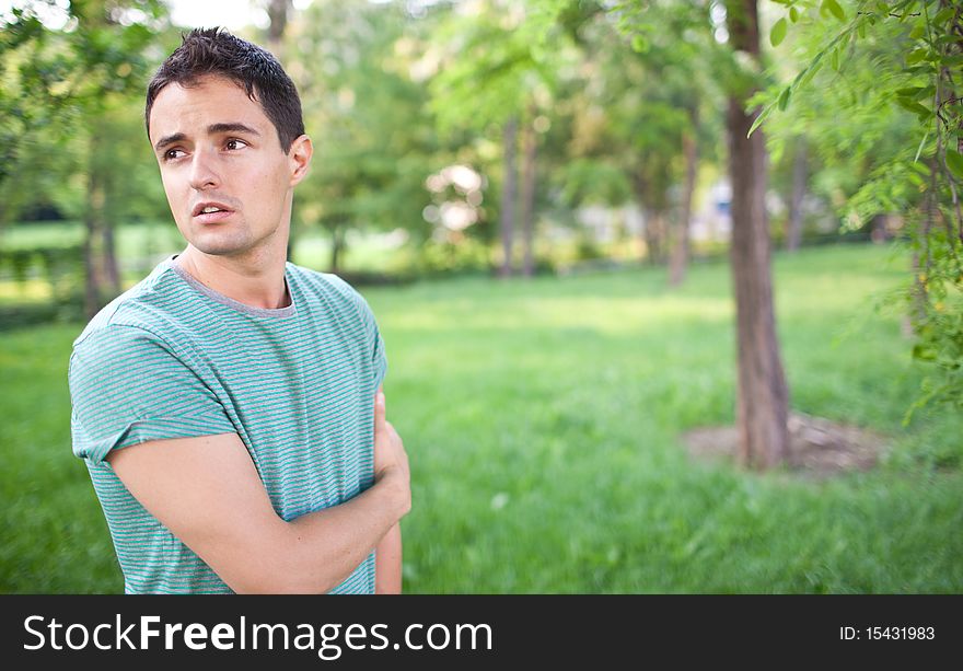 Portrait of a handsome young man while outdoors in a park on a lovely summer day