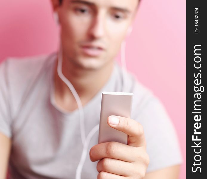 Young handsome man listening to the music on his portable mp3 player in his room