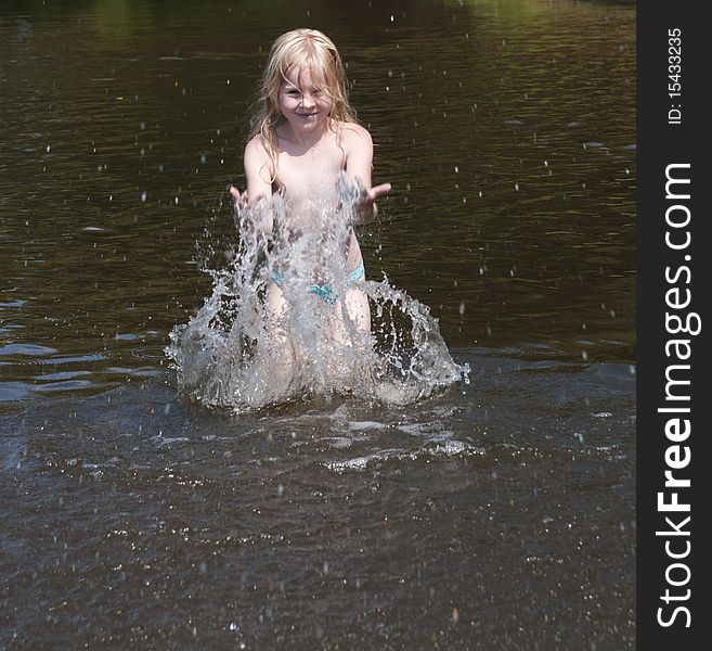 Little girl splashes with water in river