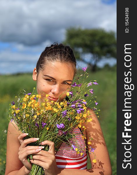 Beautiful girl is gathering bouquet of wildflowers