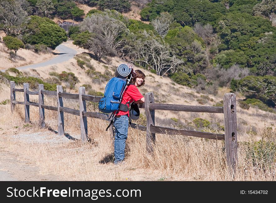 Teen resting on wooden fence enjoying views while backpacking. Teen resting on wooden fence enjoying views while backpacking.