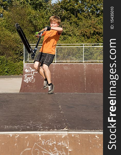 Boy with scooter at the skate parc going airborne
