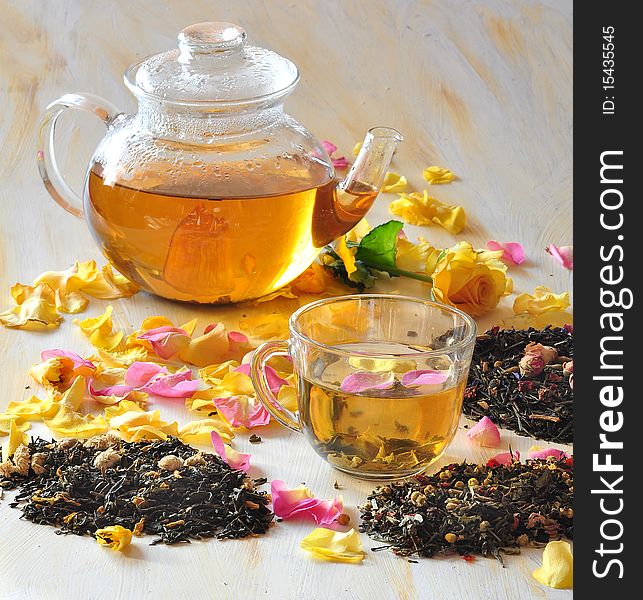 Tea is brewed in a glass tea-pot, alongside cup with tea, petals of roses and dry tea coupage. Tea is brewed in a glass tea-pot, alongside cup with tea, petals of roses and dry tea coupage
