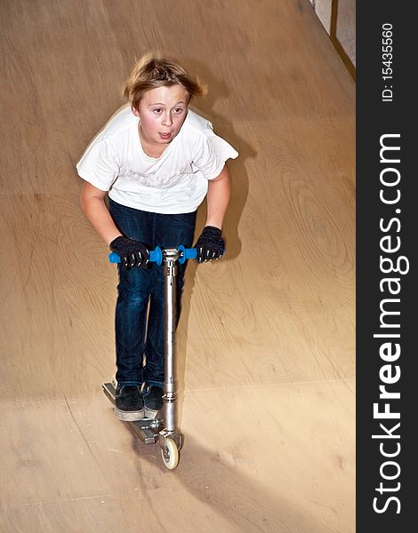 Boy is scooting with his scooter in a indoor hall. Boy is scooting with his scooter in a indoor hall