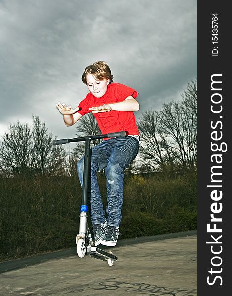 Boy riding a scooter going airborne at a scooter park. Boy riding a scooter going airborne at a scooter park