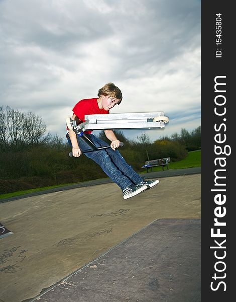 Boy riding a scooter going airborne at a scooter park. Boy riding a scooter going airborne at a scooter park