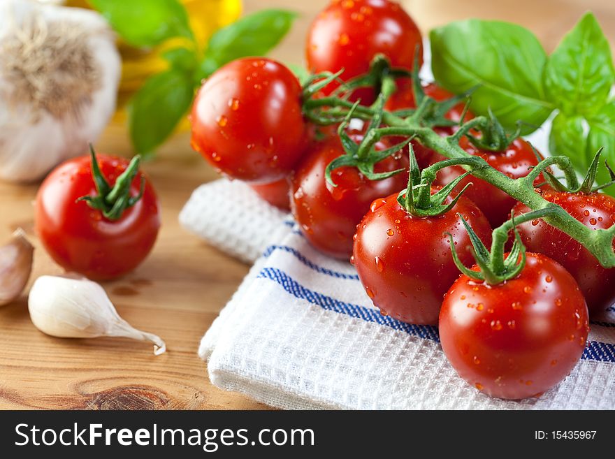 Fresh cherry tomatoes,garlic and basil on kitchen table. Fresh cherry tomatoes,garlic and basil on kitchen table