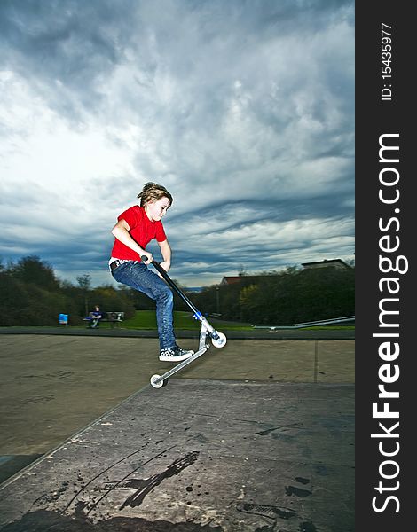 Boy riding a scooter going airborne at a scooter park. Boy riding a scooter going airborne at a scooter park