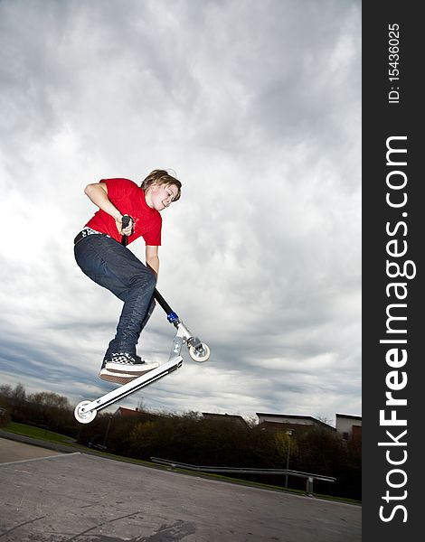 Boy riding a scooter going airborne at a scooter park. Boy riding a scooter going airborne at a scooter park