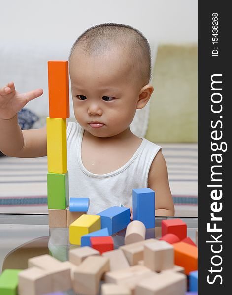 A chinese child is playing with wooden toy blocks in home.