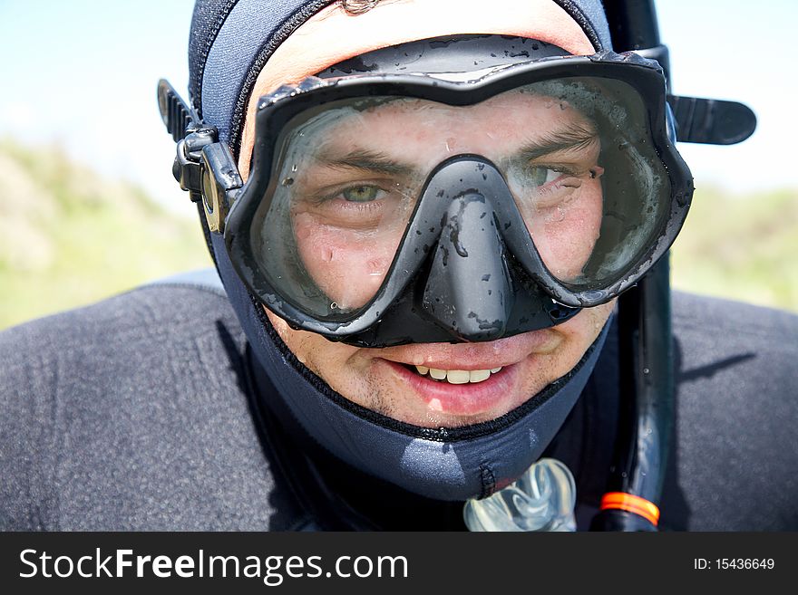 Portrait of diver in diving suit and mask with smile on his face. Close-up