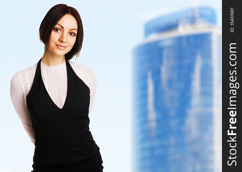 Young beautiful businesswoman against blue sky and modern building