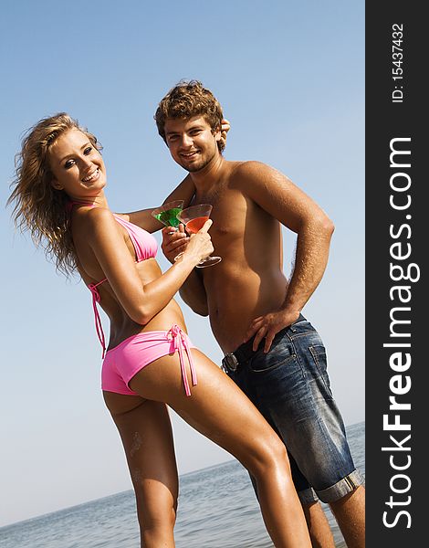 Young Couple With Cocktails On The Seaside