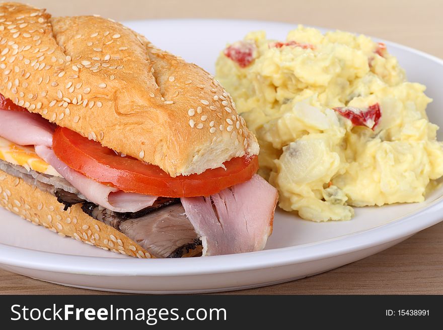 Sub sandwich with roast beef, ham, cheese and tomato along with potato salad. Sub sandwich with roast beef, ham, cheese and tomato along with potato salad