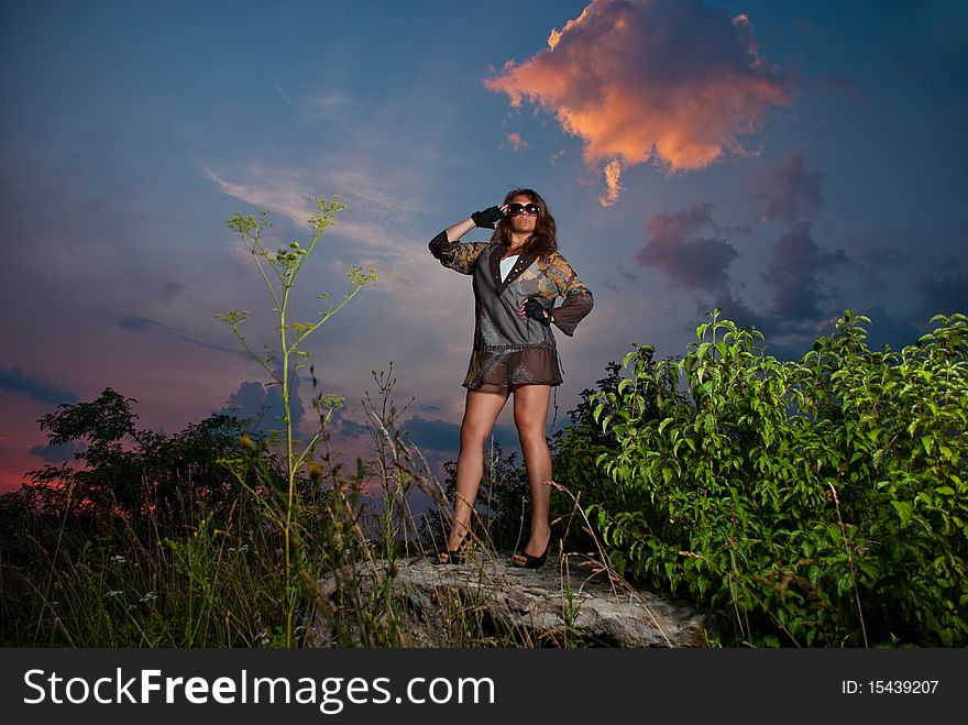 Young woman make salute at sunset rock