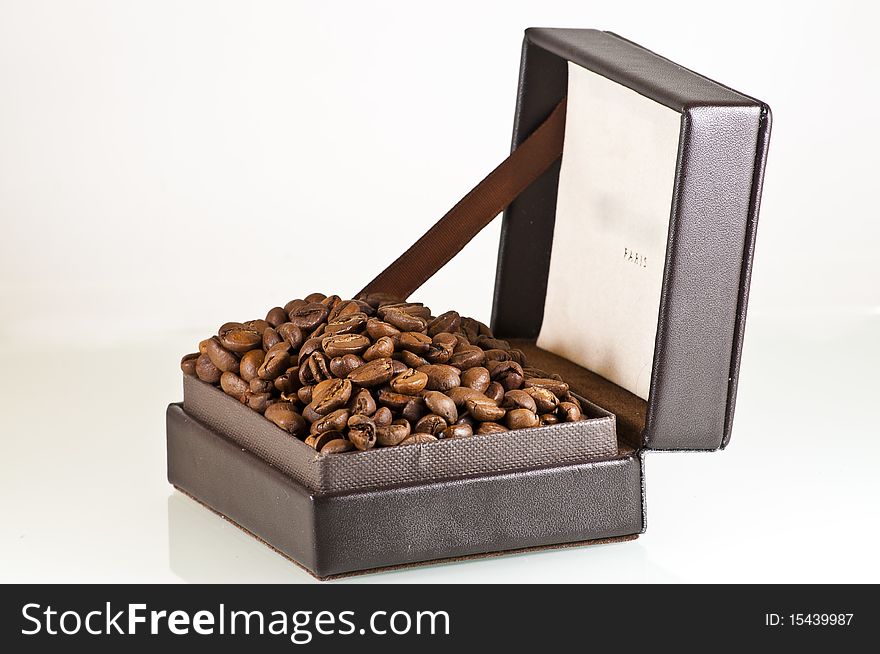 Broun leather box full of coffee seeds isolated