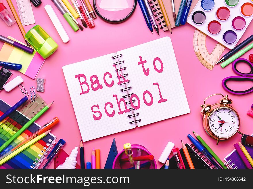 Back to school background with printed text, notebooks, pens, pencils, other stationery on pink modern background, education