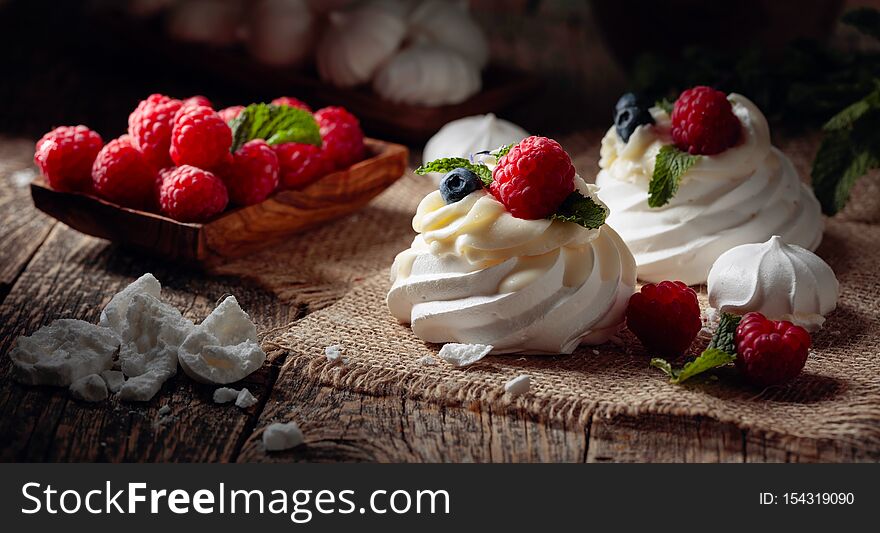 Dessert Pavlova with raspberries, blueberries and mint on a old wooden table