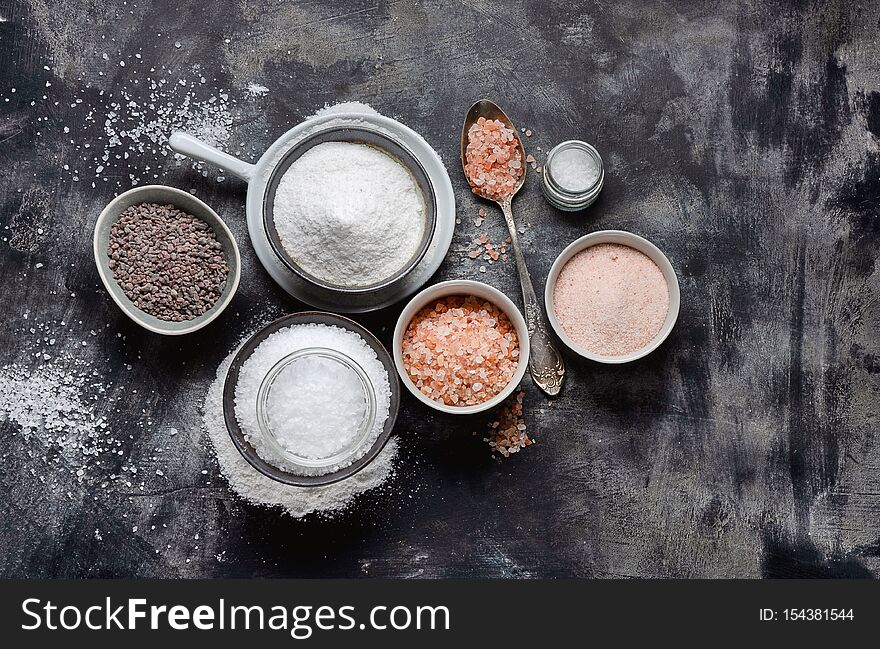 Types of salt on black background. Top view with copy space