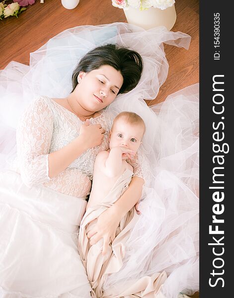 Young mom with a baby in her arms in the bright boudoir bedroom