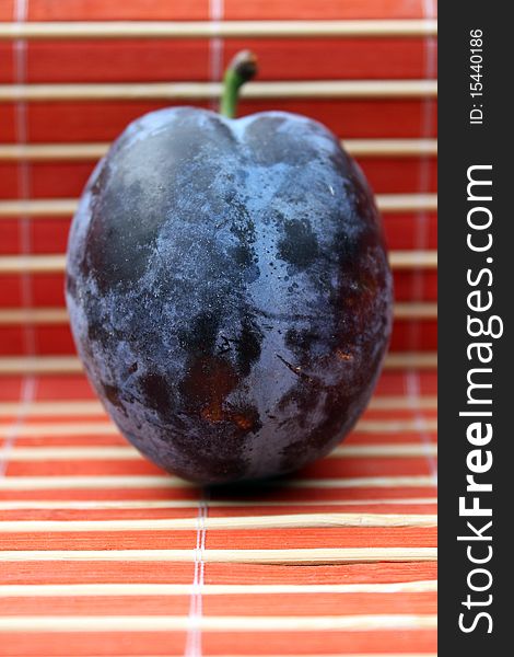 One fresh plum in abstract red background